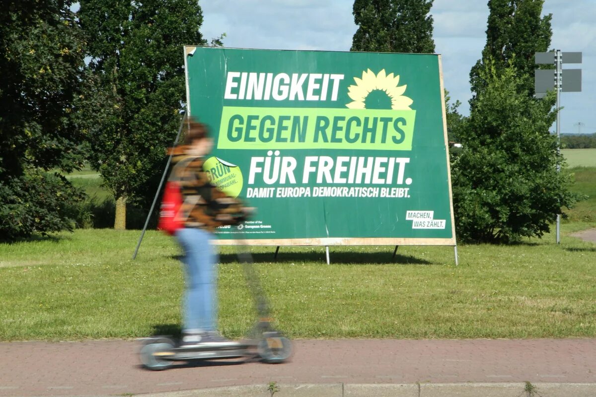 Europawahl 2024: Wahlplakat von Bündnis 90/Die Grünen Wahlplakat der Grünen mit dem Schriftzug Gegen Rechts im Mittelpunkt. Im Vordergrund fährt eine Person auf einem Roller vorbei.