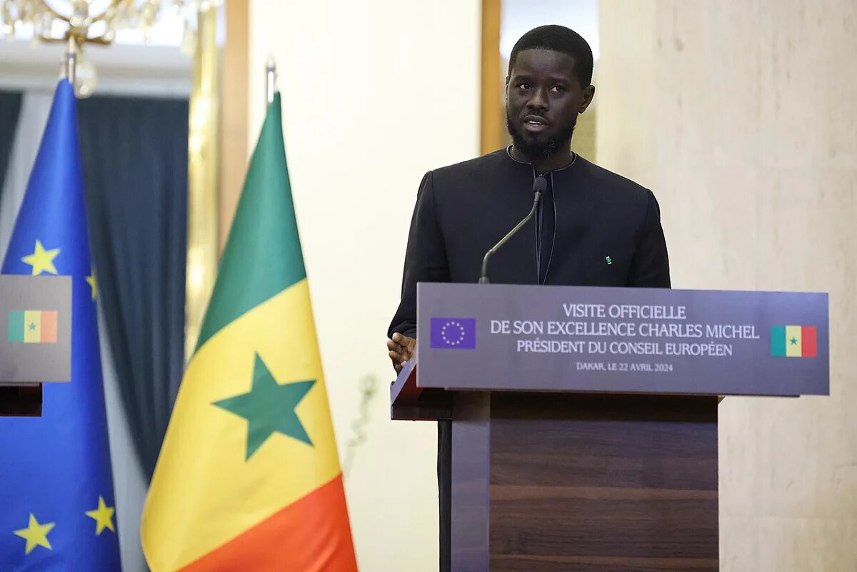 Präsident Bassirou Diomaye Faye Foto: Präsident Bassirou Diomaye Faye spricht bei einer Veranstaltung in Dakar am Rednerpult. Im Hintergrund sind die Flaggen der EU und des Senegal.