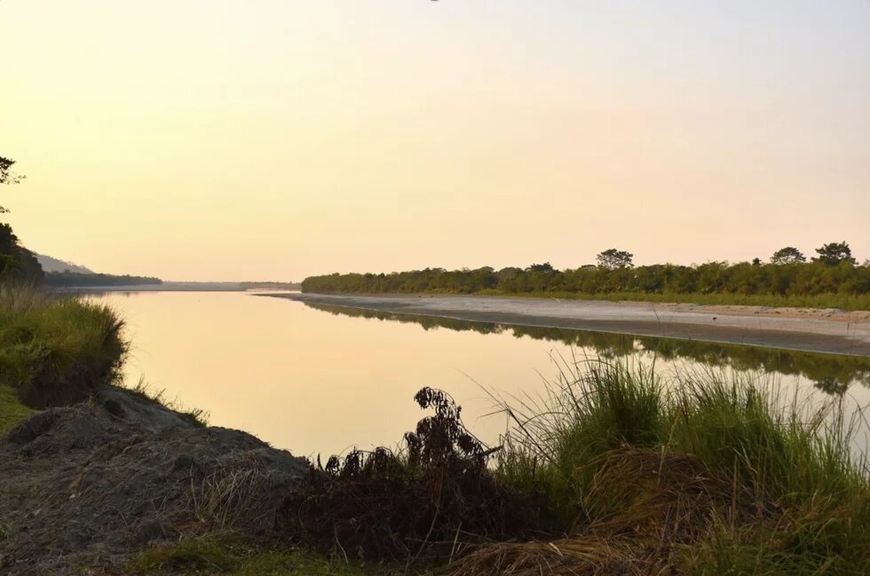Ein Fluss im Dämmerlicht. Es handelt sich um den Abong River im Kaziranga National Park in Assam, Indien. 
