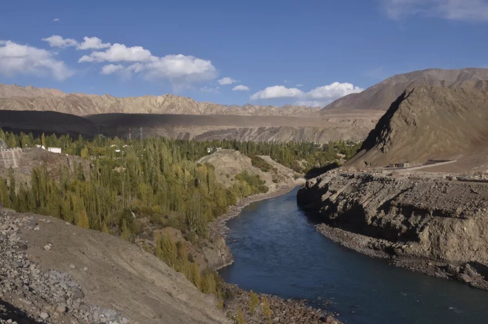 Ein Fluss fließt durch eine hügelige Landschaft, es handelt sich um den Fluss Indus in Leh, Indien. 