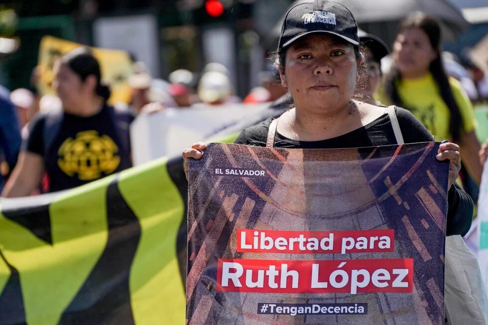 „Freiheit für Ruth López", Demonstration in San Salvador, Juni 2025 Person hält Banner mit Aufschrift „Freiheit für Ruth López (#HabtAnstand)“ („Libertad para Ruth López (#TenganDecencia)“) bei Demo, weitere Teilnehmer*innen im Hintergrund.