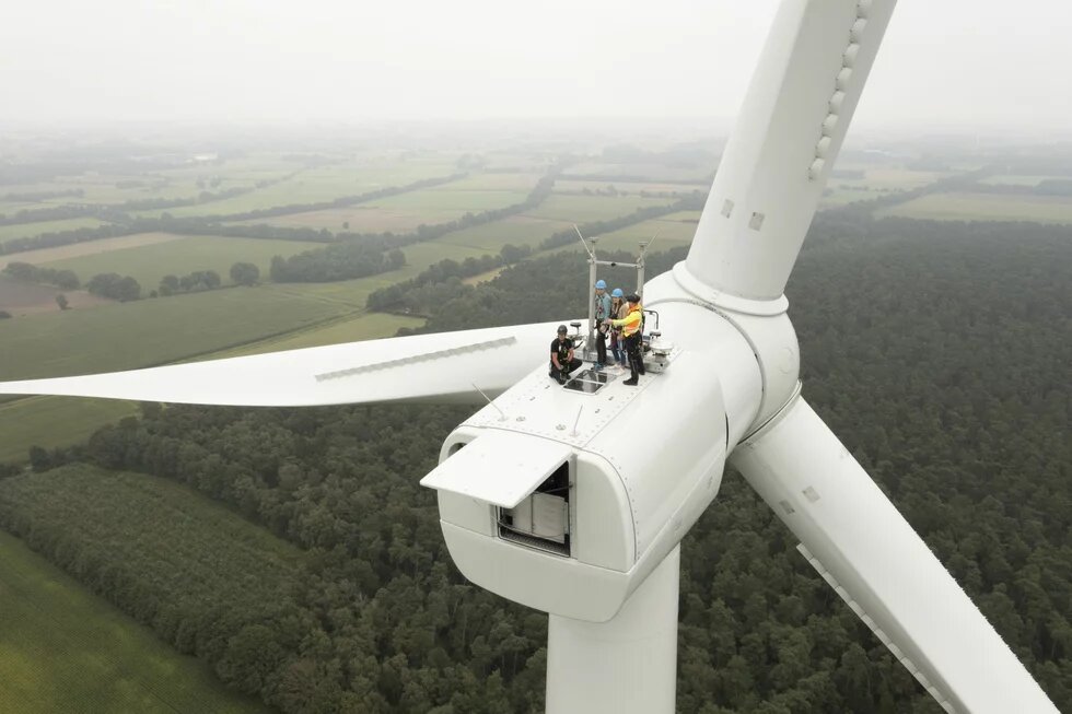 Windpark Letter Bruch Mehrere Personen stehen gesichert auf dem Maschinenhaus einer Windkraftanlage über bewaldeter Landschaft.