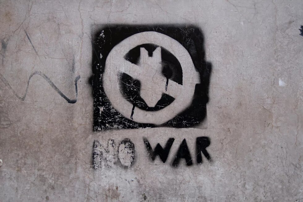 Ein Graffiti zeigt die durchgestrichene Silhouette einer herabfallenden Bombe, darunter die Unterschrift "NO WAR"