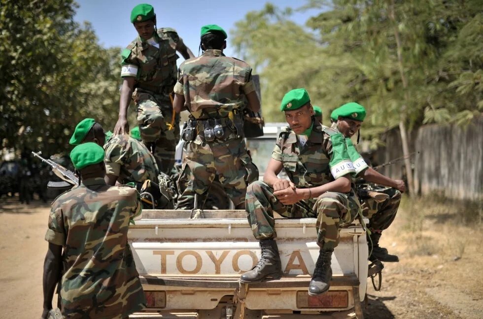 Ethopian soldiers sitting on a Toyota pickup. Several armed soldiers with green berets sit and stand on an open Toyota pickup in a dry environment.