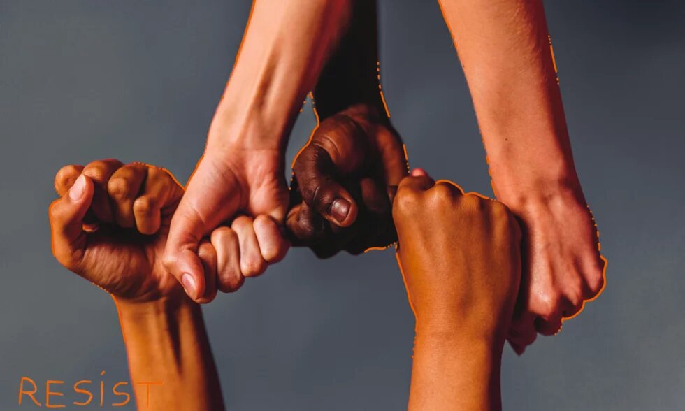 Five fists of different skin tones are clenched together, with “RESIST” written in orange at the bottom left.