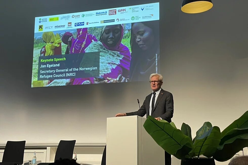 Jan Egeland at the Conference "Sudan – Thinking Peace and humanitarian Protection from a civilian perspective" A man speaks at a podium in front of a screen reading: “Keynote Speech Jan Egeland, Norwegian Refugee Council (NRC)”.