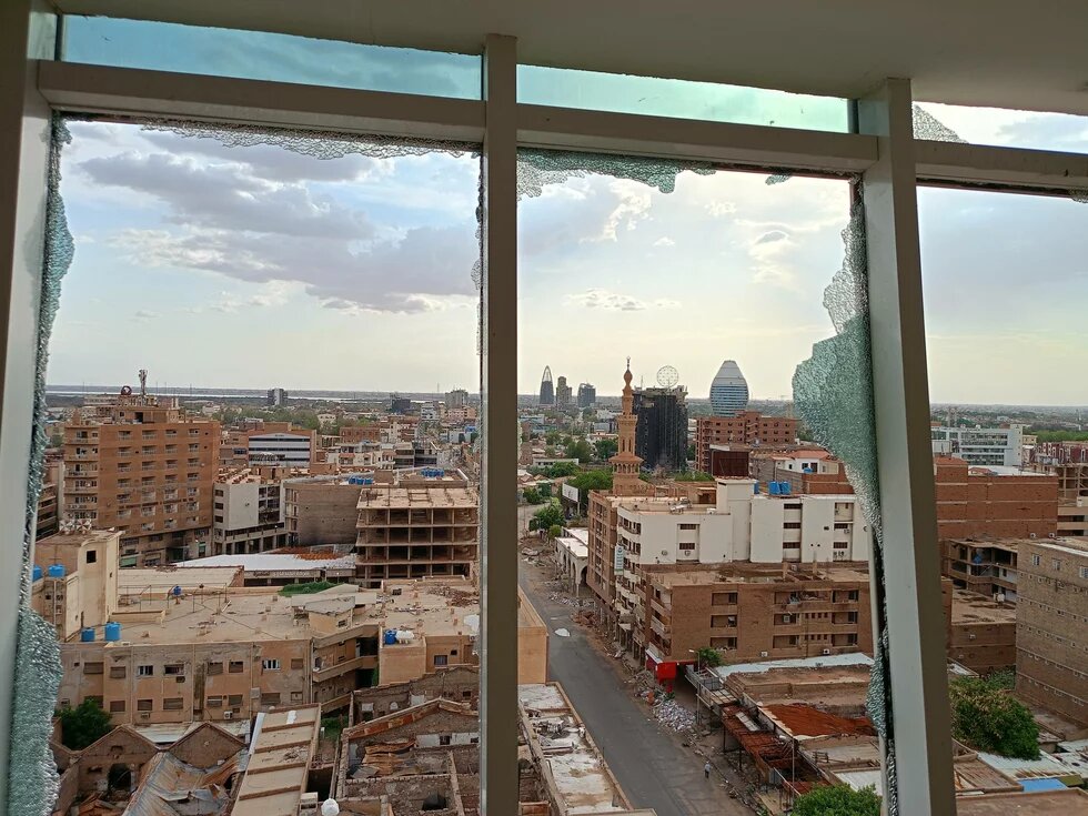 Blick einem kaputten Fenster auf das zerstörte Zentrum von Khartum, Sudan.