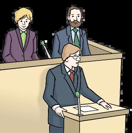 Eine Person spricht an einem Redepult mit Mikrofon, zwei weitere stehen dahinter in einem erhöhten Bereich mit eigenen Mikrofonen.