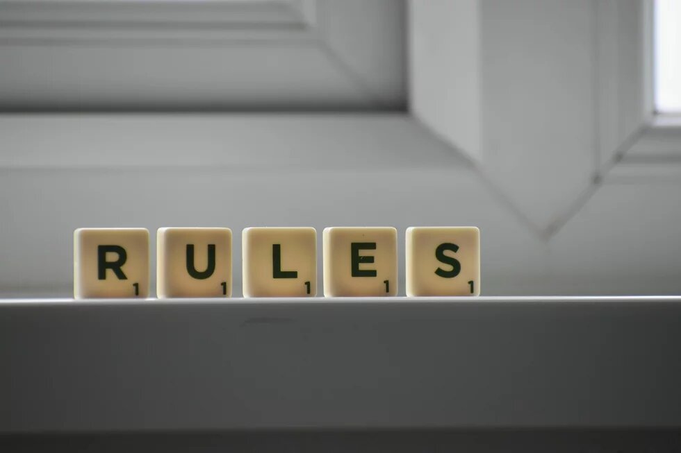 Fünf Spielsteinwürfel mit dem Wort „RULES“ (Regeln) stehen auf einer Fensterbank.