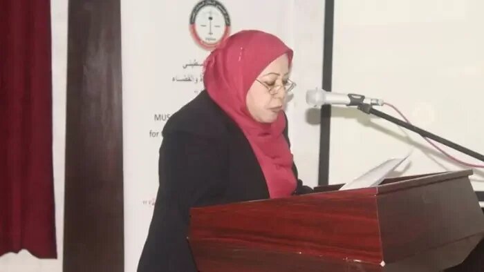 Frau (Islah Hassniyyeh) mit rotem Kopftuch am Rednerpult