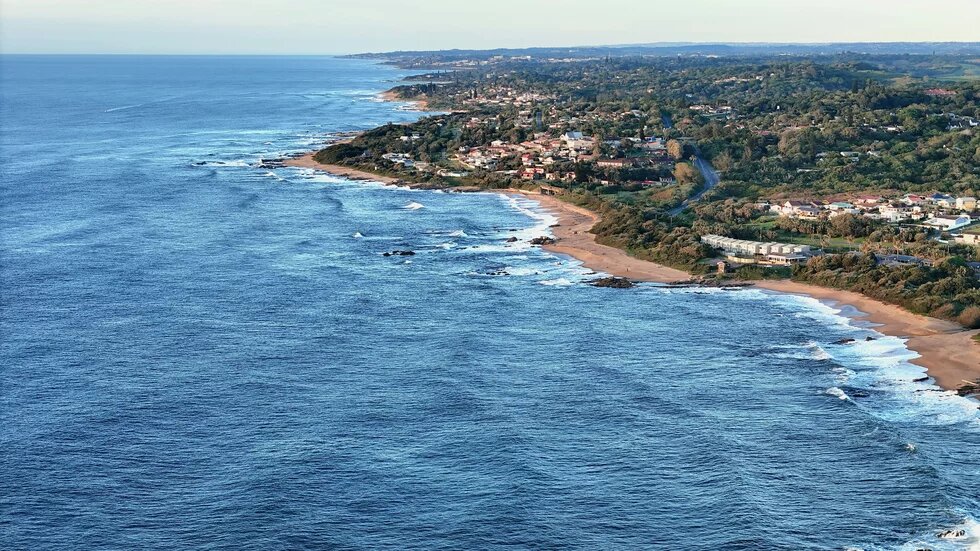 Coastline with a few villages on the right, sea on the left, sandy beaches, and scattered rocks along the shore.