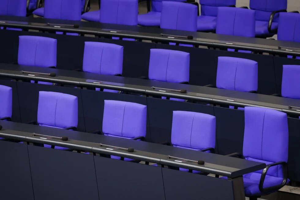 Reihen leerer Sitze mit Mikrofonen im Plenarsaal des Deutschen Bundestages.