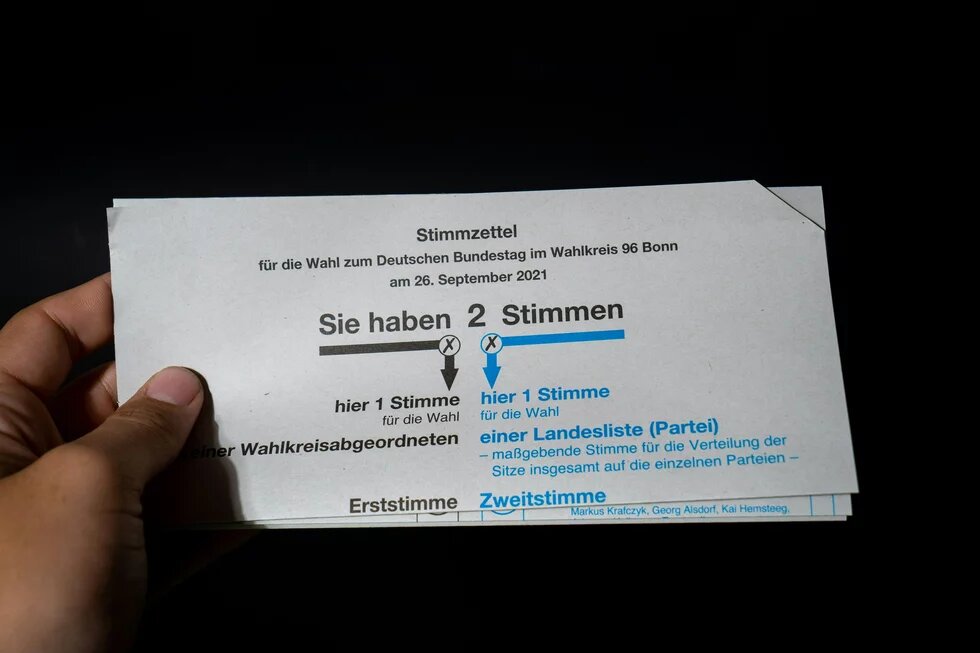 Hand hält Stimmzettel zur Bundestagswahl 2021 im Wahlkreis Bonn mit zwei markierten Kreuzen.