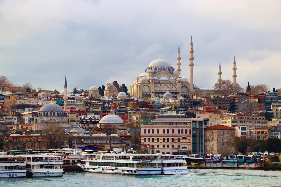 Blick über das Wasser auf Istanbul mit der Süleymaniye-Moschee, Fähren im Vordergrund und dicht bebautem Stadtgebiet.