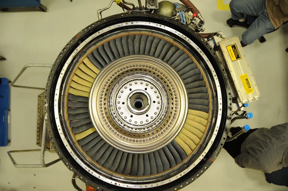 Top view of a gas turbine with a circular array of turbine blades and exposed mechanical components.