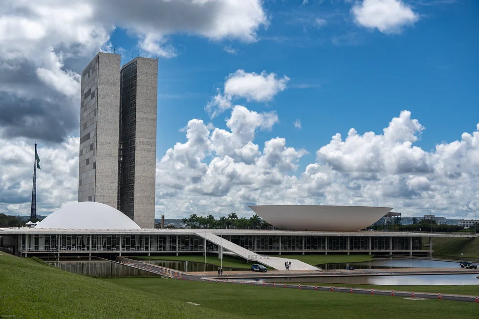 Modernes Regierungsgebäude mit zwei hohen Türmen und flachen Kuppelbauten unter blauem, wolkigem Himmel.