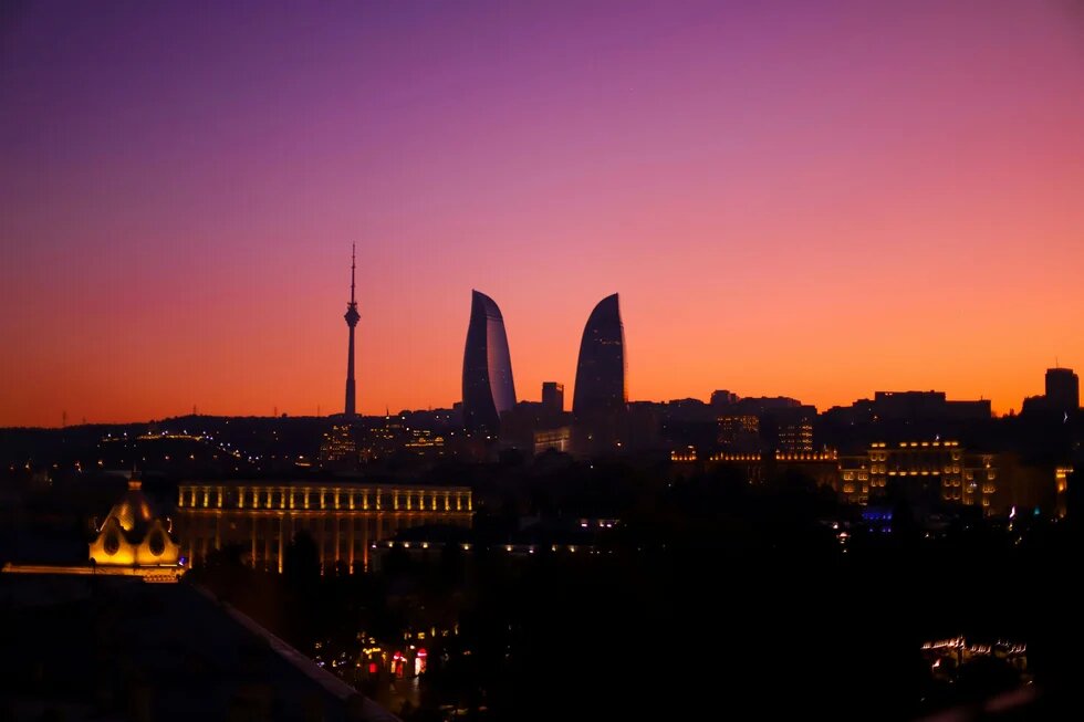 The dark skyline of Baku at sunset. The sky ranges from orange to purple.