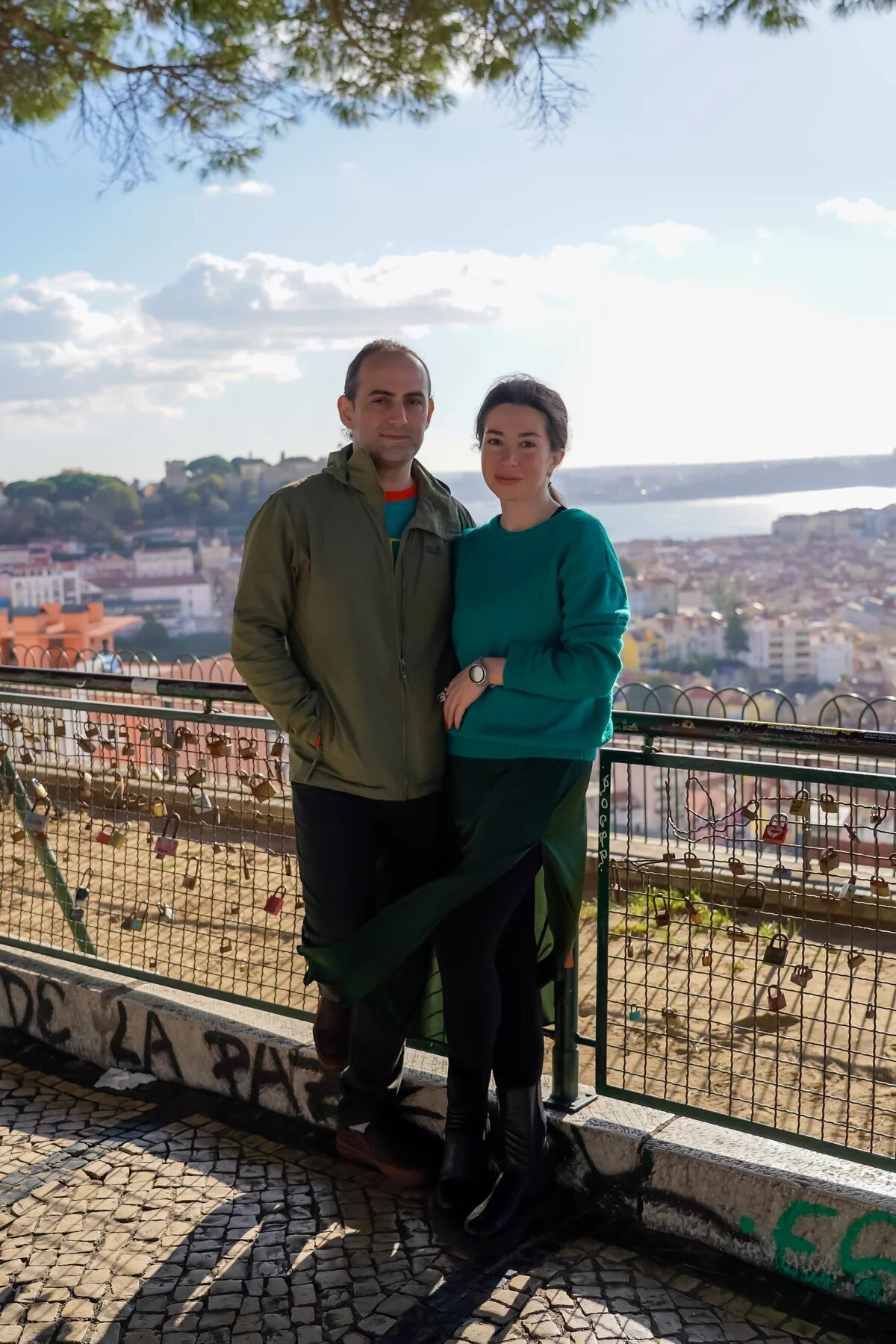  Zwei Personen stehen an einem Aussichtspunkt mit Blick auf eine Stadt und das Wasser.