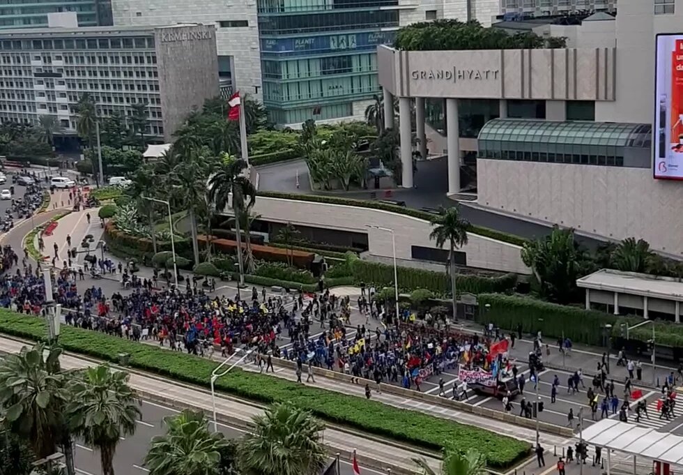 Menschenmenge bei einer Demonstration vor dem Grand Hyatt in Jakarta. Einige tragen farbige Kleidung und Fahnen.