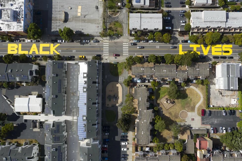 Eine Straße von oben fotografiert. 'Black Lives Matter' ist in Gelb auf der Straße gesprüht