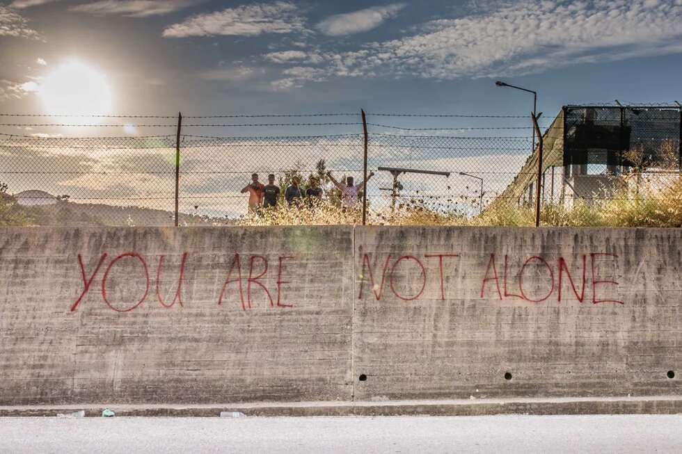 August 2015, Moria (Lesbos), Griechenland Das Erstaufnahmelager in Moria wurde ursprünglich als Abschiebelager gebaut und wirkt wie ein großes Gefängnis. Aus Protest wurden Solidaritätsbotschaften an den Außenwänden hinterlassen (aufgenommen in Moria (Lesbos), Griechenland, August 2015)