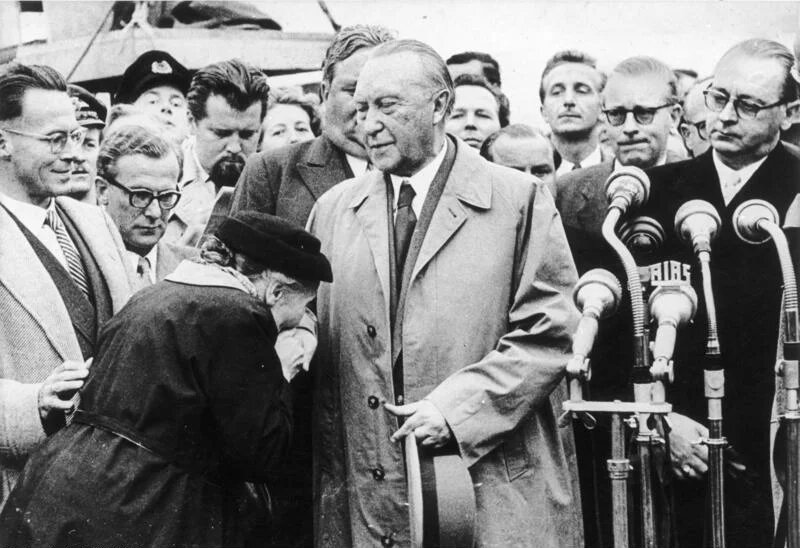 Köln/Bonn, Adenauer, Mutter eines Kriegsgefangenen Flughafen Köln/Bonn.- Alte Frau küsst Konrad Adenauer die Hand; rechts: Bundesaußenminister Heinrich von Brentano