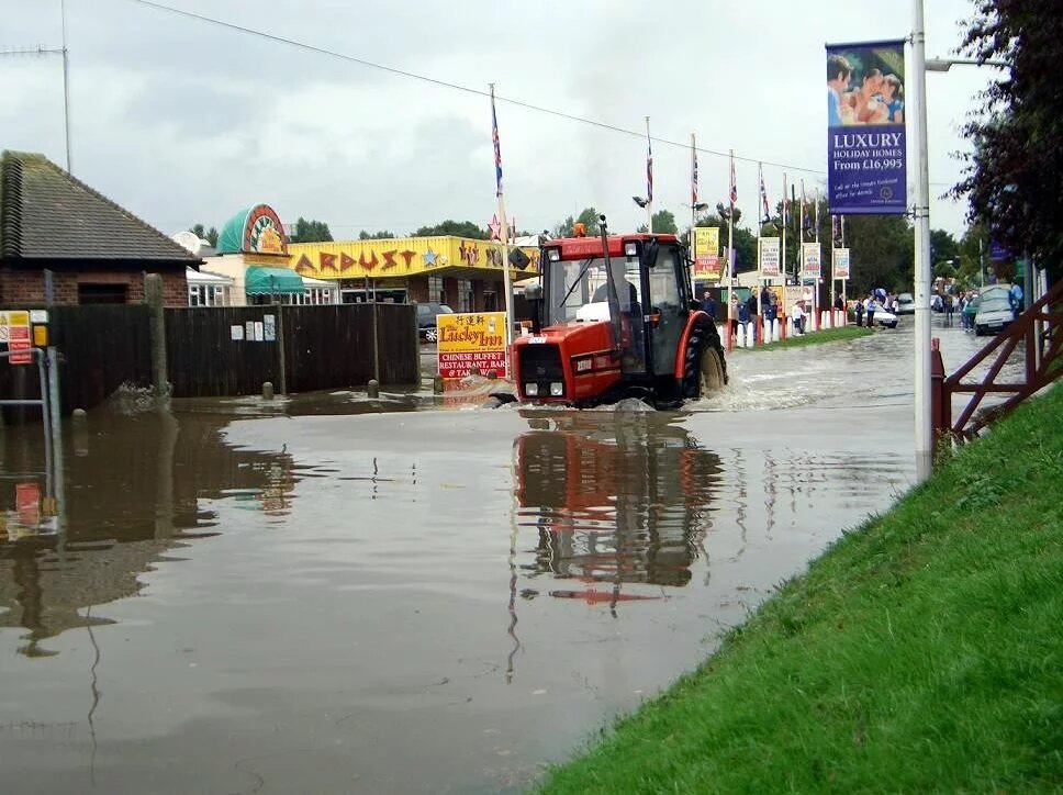 Hopton Flooding Norfolk Ein Traktor fährt durch eine teife Pfütze