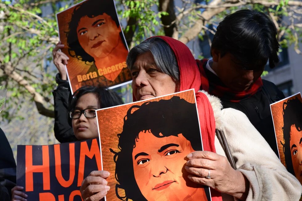 Demonstrant/innen mit Plakaten protestieren für Gerechtigkeit im Mordfall Berta Caceres