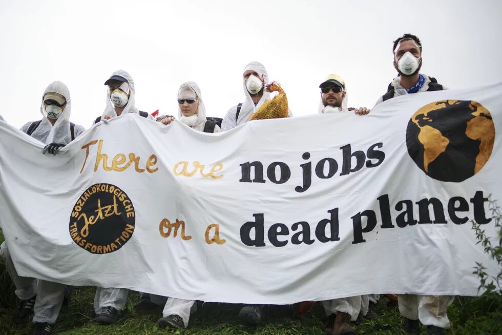 Lehren aus der Kohlekommission Lehren aus der Kohlekommission: Eine Gruppe in weiß gekleideter Protestant/innen hält ein Banner mit der Aufschrift "there are no jobs on a dead planet".