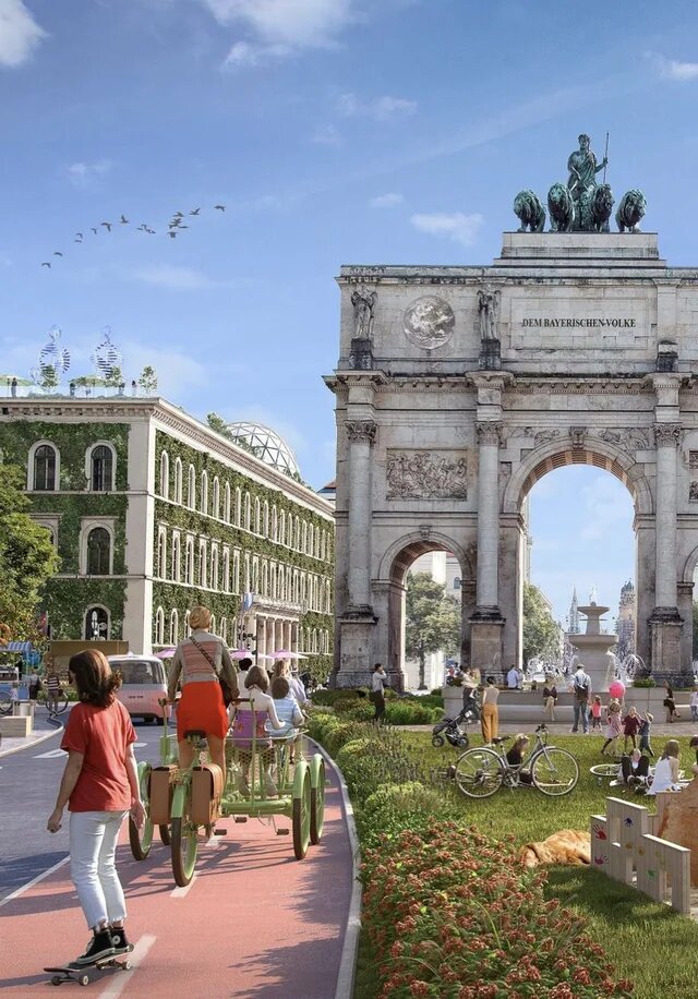 Belebte Grünfläche vor dem Siegestor in München mit Radweg, Fußgänger*innen, Fahrrädern und üppiger Bepflanzung auch an Fassaden