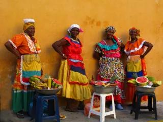 Women in colourfull colombian dresses. 40 Years of the CEDAW in Colombia - Picture: Four colourfully dressed women selling fruit on the street.