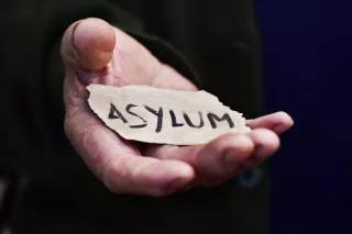 Asylum Offene Hand in der ein abgerissener Zettel liegt, auf dem Asylum steht