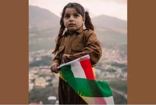 Kind mit kurdischer Flagge in traditionell kurdischer Kleidung