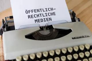 Ein Blatt Papier, auf dem "Öffentlich-Rechtliche Medien" steht, steckt in einer Schreibmaschine.