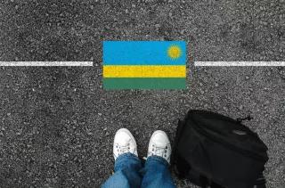 Abschibung nach Ruanda Füße vor eine symbolischen Grenzlinie mit der Flagge des afrikanischen Lands Ruanda
