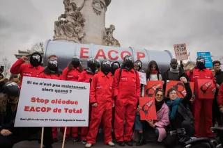 Aktivisten in roten Squid-Game-Kostümen mit Total-Energies-Logo auf Masken halten eine gefälschte Pipeline, um Total aufzufordern, sich von fossilen Brennstoffen zu trennen. Eine Delegation ugandischer Aktivisten schließt sich dem STOP EACOP-Block beim Look UP-Klimamarsch in Paris, Frankreich, an, um das klimaschädliche Projekt von Total, die East Africa Crude Oil Pipeline, anzuprangern. Aktivisten in roten Squid-Game-Kostümen mit Total-Energies-Logo auf Masken halten eine gefälschte Pipeline, um Total aufzufordern, sich von fossilen Brennstoffen zu trennen.