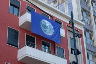 Büro der Heinrich-Böll-Stiftung in Tirana Büro der Heinrich-Böll-Stiftung in Tirana - rotes, mehrstöckiges Gebäude mit am Balkon hängenden blauen Fahne mit Erdkugel
