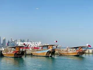Drei Boote an einem Anlegesteg vor einem Schild mit 'FIFA World Cup Qatar 2022'