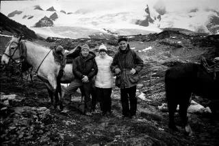 Ein schwarz-weißes Bild Yvon Chouinard, Chris Tompkins und Doug Tompkins zusammen in den Bergen. Es gibt zwei Pferde neben der Kleingruppe
