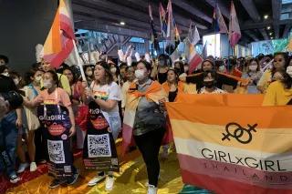Pride 2022 in Bangkok Weiblich gelsene Personen mit Fahnen und Transparenten laufen über eien große Regenbogen-Fahne