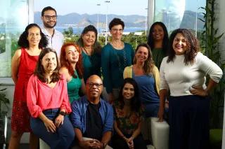 Team Büro Brasilien Teamfoto: Elf Menschen sitzen bzw. stehen zusammen vor einem Fenster