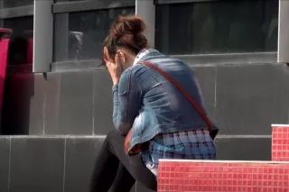 Frau mit dem Rücken zum/zur Betrachter/Betrachterin sitzend, die Hände vor dem Gesicht Frau mit dem Rücken zum/zur Betrachter/Betrachterin sitzend, die Hände vor dem Gesicht