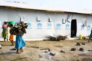 Frau trägt Feuerholz zum Flüchtlingslager