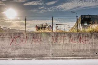 August 2015, Moria (Lesbos), Griechenland Das Erstaufnahmelager in Moria wurde ursprünglich als Abschiebelager gebaut und wirkt wie ein großes Gefängnis. Aus Protest wurden Solidaritätsbotschaften an den Außenwänden hinterlassen (aufgenommen in Moria (Lesbos), Griechenland, August 2015)