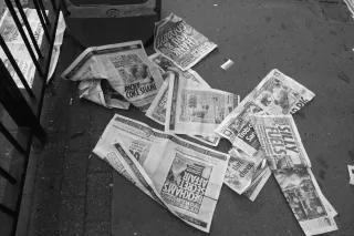 A tattered boulevard newspaper is laying on the ground