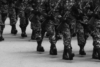 Mas si osare.. Marschierende Soldat/innen mit Maschinengewehren bei einer Parade