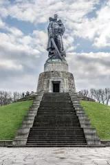 Denkmal eines Mannes mit Schwert in der Hand und Kind auf dem Arm, auf einem kaputten Hakenkreuz stehend 