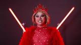 Eine Drag Queen in rot steht vor einem roten Hintergrund