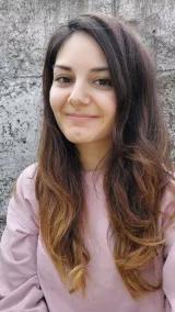 Selen Sarikaya hat lange braune Haare und blickt lächelnd in die Kamera