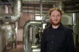 Raphael Gruseck Raphael Gruseck im Hintergrund die silbernen Rohre Heizungsanlage